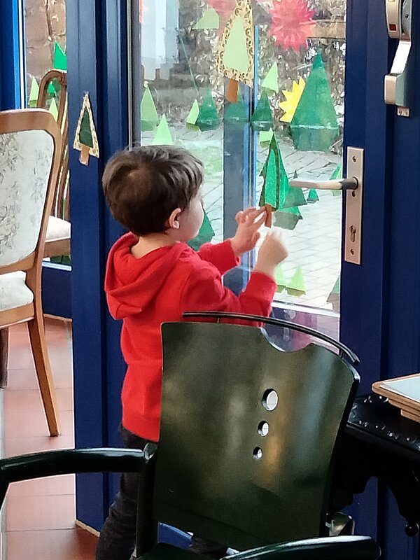 Junge beklebt Fenster mit Weihnachtsdekoration