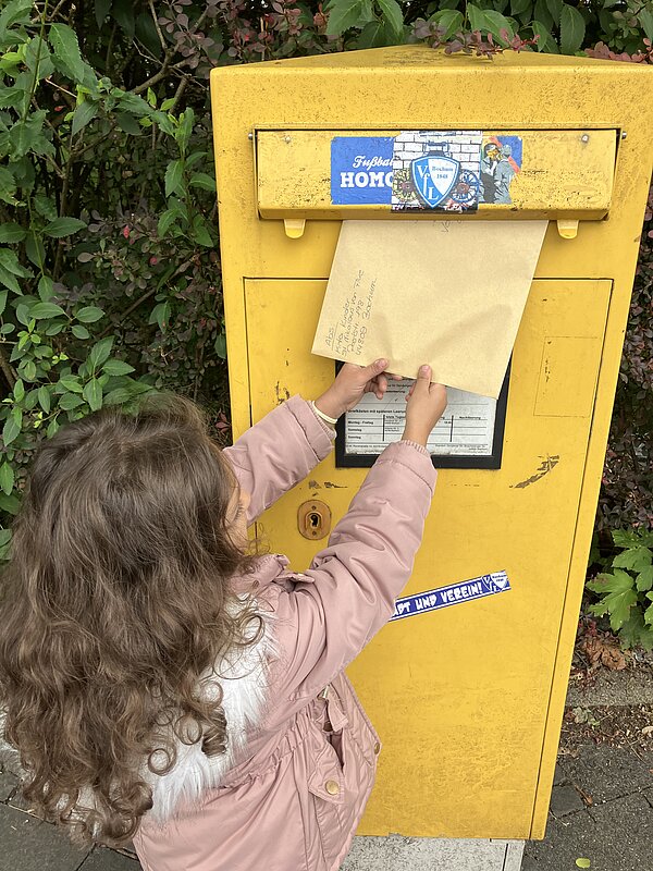 Kind wirft Brief in Briefkasten