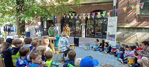 Kinder sitzen im Kreis und hören Vorgelesenem zu