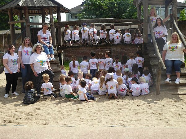 Gruppenfoto, alle tragen Shirts mit buntem Adler